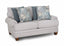 The Annisa Julien Cork Loveseat 95720-3574-20 by Franklin Furniture Corp. showcases a light gray upholstery with rolled arms, wooden legs, and the WOW Seating System. Its reversible seat and back cushions provide lasting comfort. This loveseat comes with four throw pillows—two in blue-gray and two featuring a blue floral pattern—and is displayed against a white background.