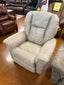 A spacious and plush La-Z-Boy Jasper Recliner 709-10-D1825-35 in beige, featuring wide padded arms and a supportive backrest, is showcased in a furniture store, providing the comfort of a wide seat recliner surrounded by other recliners and sofas in the background.