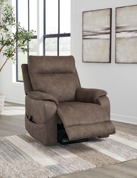 A brown faux leather Crestmeade Espresso Lift Chair 1350412 power lift recliner with a remote control hanging from the side pocket.