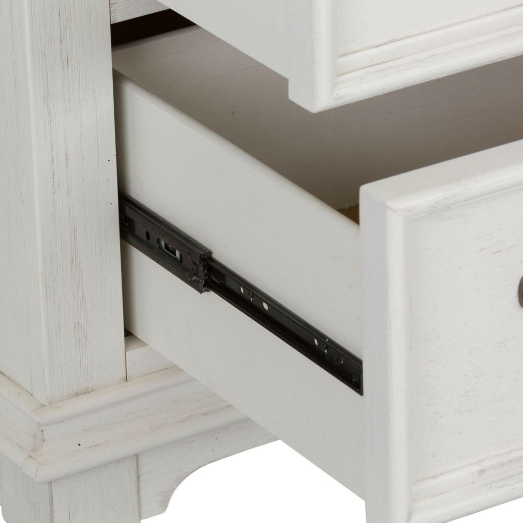A close-up of a white wooden dresser with one drawer partially open, revealing the metal sliding track on the side.