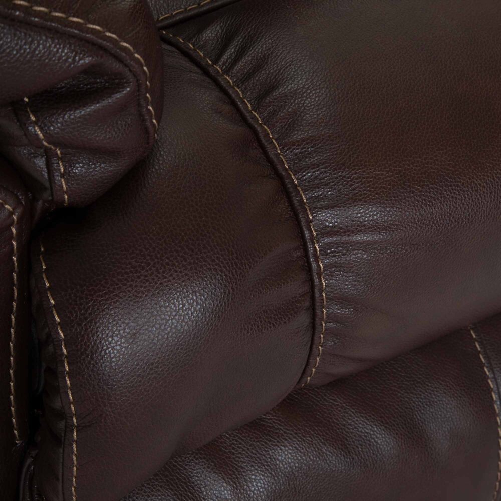 Close-up of dark brown leather upholstery with visible stitching and a padded, tufted texture—signature details of the Connery Blaze Bourbon Recliner 4703-LM99-14 by Franklin Furniture Corp. The supple surface is paired with a Gel-blended Foam Cushion for enhanced comfort, making this Leather Rocker an inviting addition to any space.