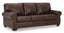 The Ashley Colleton Sofa 5210738 is a dark brown leather sofa featuring three seat cushions, three back cushions, rolled arms with brass nailhead trim, and short wooden legs. Its classic design and traditional details make it an elegant addition to any living space.