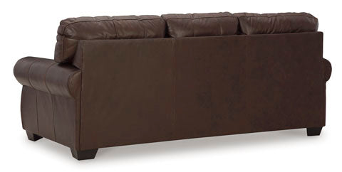 A dark brown leather Colleton Sofa 5210738 by Ashley is shown from the back, featuring three cushioned sections on top and rolled armrests, with short wood legs visible—evoking the timeless elegance of traditional design.