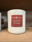 A white jar labeled Circle E Candle 14oz Country Morning rests on a brown shelf, filling the air with subtle notes of vanilla and nutmeg. The label reads, “The candle for people who know candles.” Another identical jar is partially visible in the background.