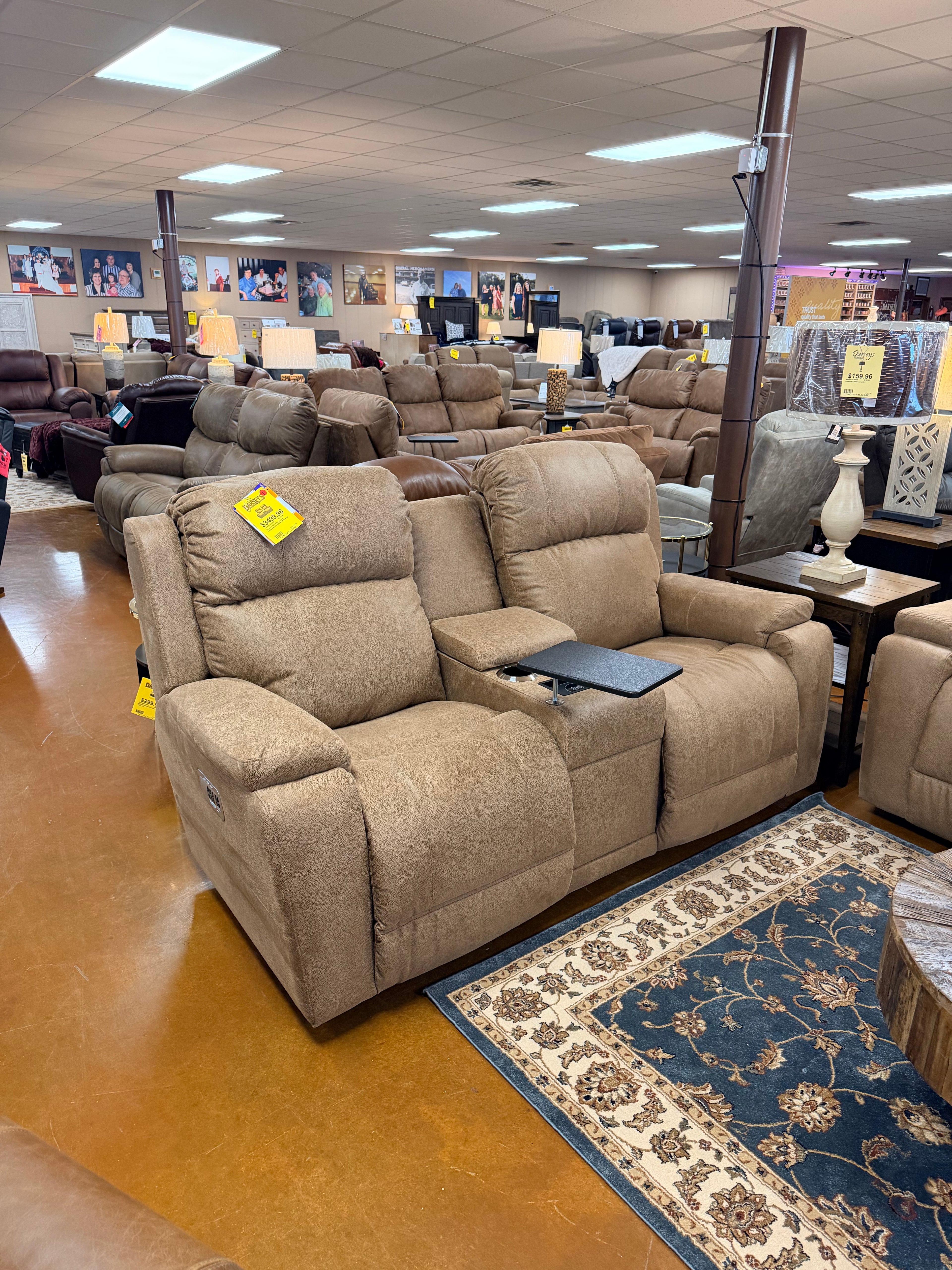 Two Dorian Power Loveseat Reclining chairs (755-X49-D1855-75), brown with center console and tray table, are showcased in a furniture store among couches and recliners under bright ceiling lights on a brown floor.