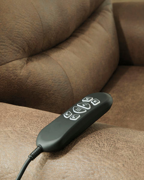 A hand-held remote controller resting on the arm of a brown Revived and Restored Earth Lift Chair 8240712 power lift recliner.