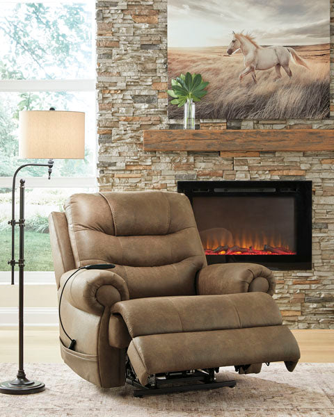 Brown Ashley Revived and Restored Earth Lift Chair 8240712 power lift recliner with a remote control, positioned in a living room in front of a stone fireplace.