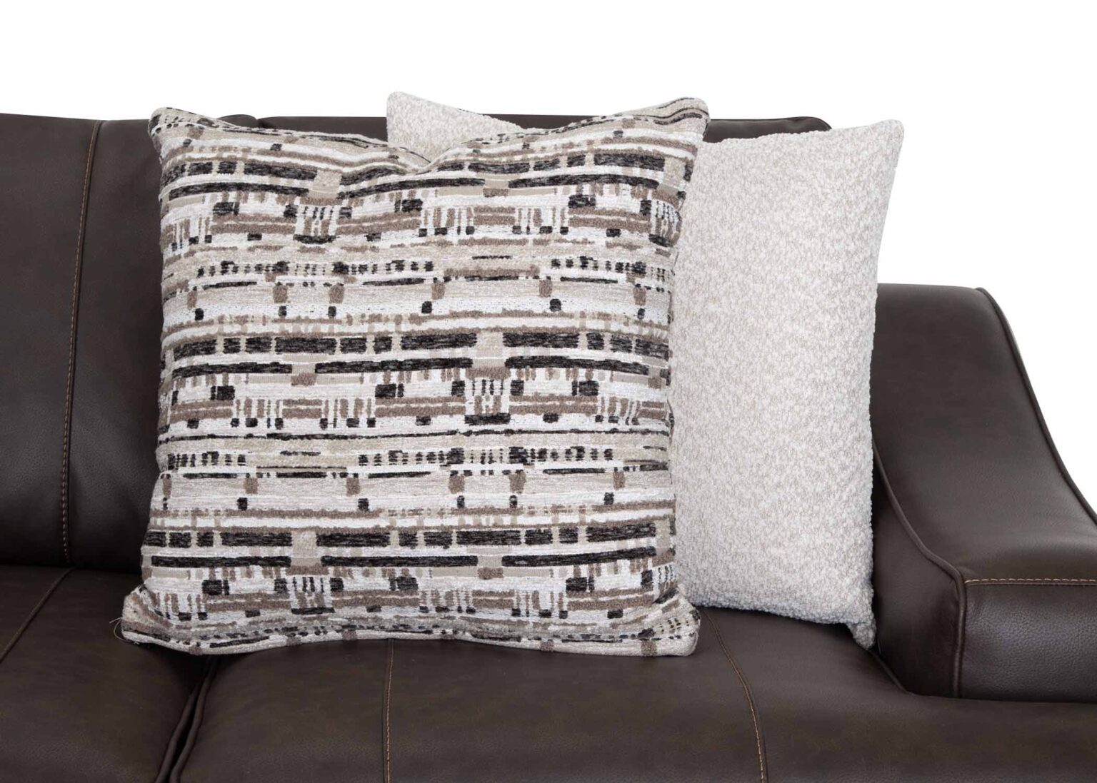 Two throw pillows rest on a Prescott Duvall Coffee Sofa 89340-3429-10 by Franklin Furniture Corp.; one pillow showcases a textured gray and white woven pattern, while the other is a solid light beige. This rich chocolate fabric sofa, part of the WOW Seating System, brings both style and comfort to any living space.