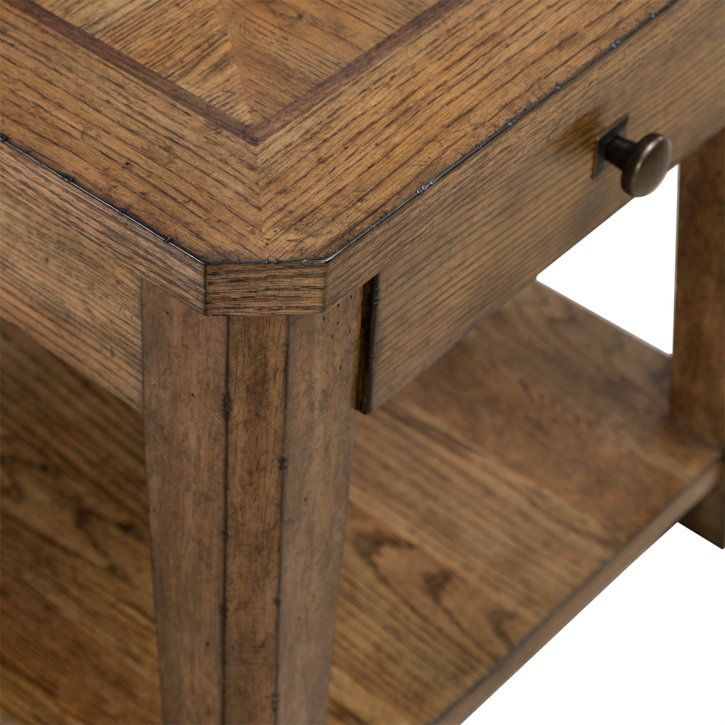 Close-up of the Liberty Furniture Carolina Park End Table 930-OT1020, featuring a storage drawer with a metal knob and a lower shelf. The white oak table showcases a natural finish with visible grain, highlighting its corner craftsmanship and surface pattern.