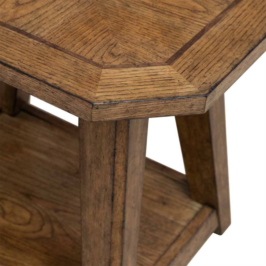 Here is a rewritten version of your sentence using the given product data: Close-up of the Liberty Furniture Carolina Park End Table 930-OT1021, showcasing an octagonal corner with a geometric tabletop pattern and lower shelf, both crafted from white oak veneers in a medium brown finish. This end table features angled legs and visible wood grain texture.