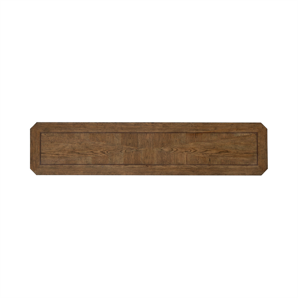 A long, rectangular wooden panel with beveled edges and a visible wood grain pattern, crafted from white oak veneers in an Amber Brown finish by Liberty Furniture. The corners are cut at an angle, giving the piece an octagonal appearance at each end—reminiscent of the refined style of the Carolina Park Sofa Table 930-OT1030.