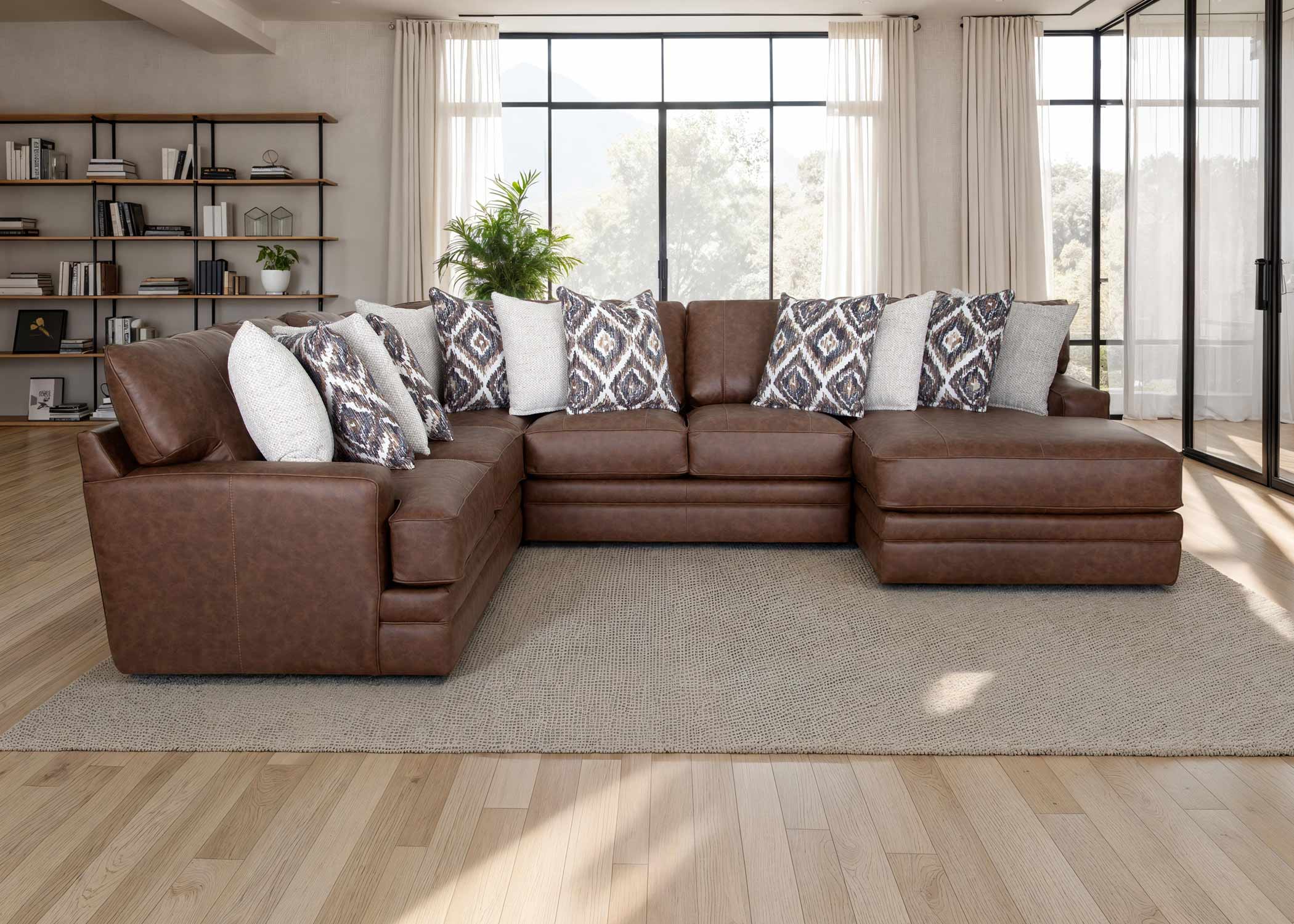 The Franklin Furniture Corp. Asheville Duvall Vintage Brown Sectional (934-04-59-69-86-3429-16) features luxurious brown leather upholstery and comes adorned with patterned and white throw pillows, arranged atop a beige rug in a bright living room with large windows, wood floors, and a bookshelf in the background. Experience unmatched comfort and timeless style with the innovative WOW Seating System built into this elegant sectional.