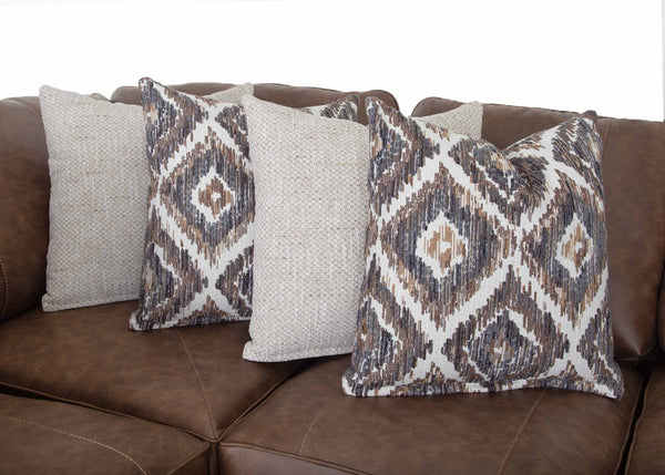 Four throw pillows are arranged on the Franklin Furniture Corp. Asheville Duvall Vintage Brown Sectional; two feature a geometric pattern in brown, beige, and gray, while the other two are a light, textured solid color.