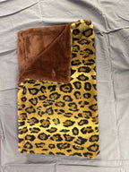 Leopard print blanket with brown backing on a gray surface
