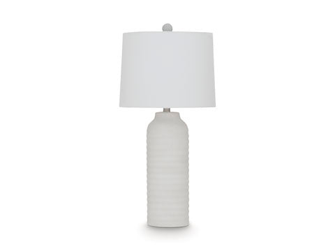 The Vauville White Lamp L243674 by Ashley features a white ceramic, textured ribbed base paired with a round white lampshade, creating a sculptural lamp silhouette that adds contemporary elegance to any space. Photographed against a plain white background, this table lamp from Ashley seamlessly blends style and functionality.
