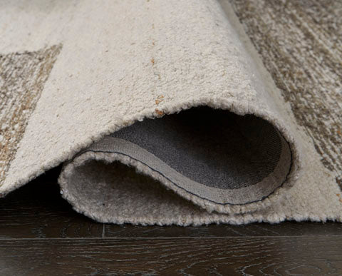 A 5 x 7 handwoven Barus Rug R406402 with a cream and brown geometric pattern, shown with one corner rolled back to reveal the underside.