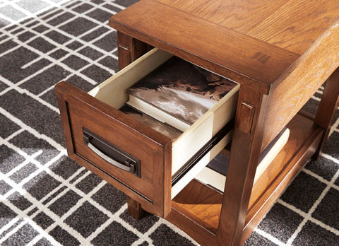 Breegin Brown Chairside End Table T007-319 in a Mission-style with an open drawer containing two books and a lower storage shelf, positioned on a black and white patterned rug.