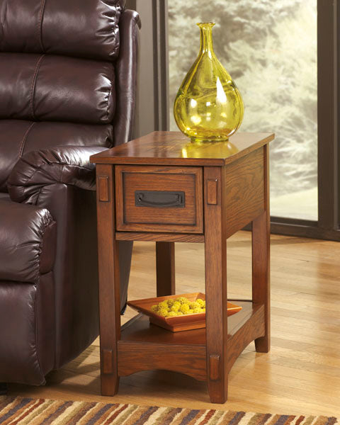 Breegin Brown Chairside End Table T007-319, a narrow brown wooden Mission-style end table with one drawer and a bottom shelf, topped with a yellow glass vase.