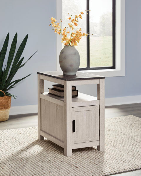 Fendenmore White Chairside End Table T190-217 featuring a dark top, an open shelf with two books, and a storage cabinet with a black pull handle.