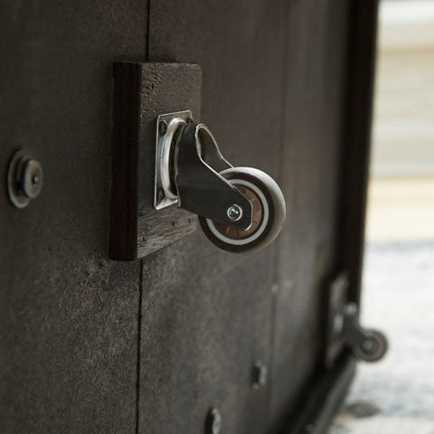 Close-up of a metal caster wheel attached to the base of a Bensonale Cocktail Table and 2 End Tables T400-13.