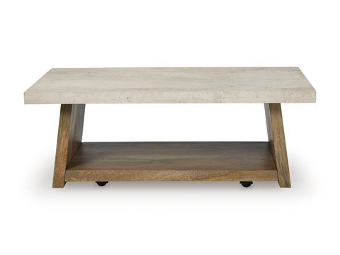 The Ashley Brendalhouse Cocktail Table T642-1 features a thick, light-colored faux cement rectangular tabletop, angled wooden legs, and a lower wooden shelf for storage, all presented against a white background.