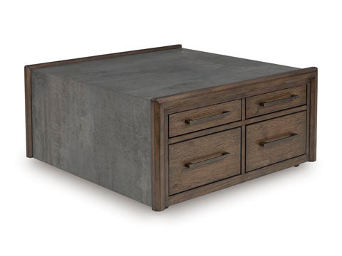 The Ashley Kallenny Cocktail Table (T669-8) features a square design with a concrete-like top and sides, complemented by four wooden drawers with metal handles on one side. With its blend of raw materials and clean lines, this table brings a strikingly modern, industrial edge to your space.