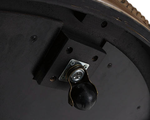 Close-up of the underside of the Ashley Camdill Coffee Table T808-8, showing a black swivel caster wheel secured with a metal bracket to the dark wooden surface.