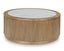The Camdill Coffee Table T808-8 by Ashley features a round silhouette with a ribbed wooden base and a smooth white marble top. This contemporary centerpiece blends natural wood tones with sleek stone, offering a modern and minimalist design for your living room.