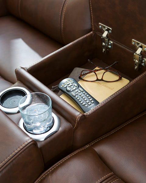 The Ashley Knightington Brown Power Reclining Loveseat (model U1160218A) features a leather armrest with an open storage compartment to conveniently hold your remote, glasses, and journal. A built-in cup holder keeps your glass of water within easy reach—making this loveseat the perfect addition to your home theater setup for a truly relaxing experience.
