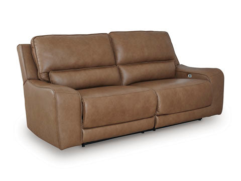 The DeepWakes Caramel Power Reclining Sofa U6260647 by Ashley features top-grain brown leather upholstery, plush cushions, and gently curved armrests, displayed against a plain white background.