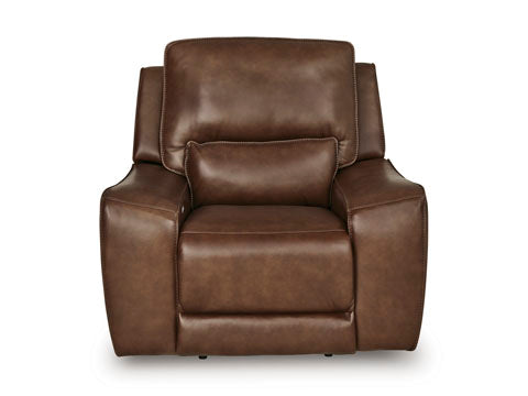 The Ashley DeepWakes Canyon Power Recliner U6260713 is a spacious recliner chair crafted in rich brown top grain leather, featuring wide armrests, a matching lumbar pillow, and an adjustable headrest, displayed against a white background.